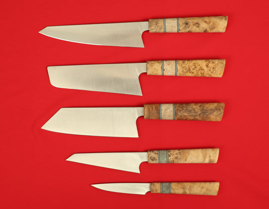 Japanese style kitchen knife set on a red background. Kiritsuke, Nakiri, Bunka, Honesuki and paring knives.