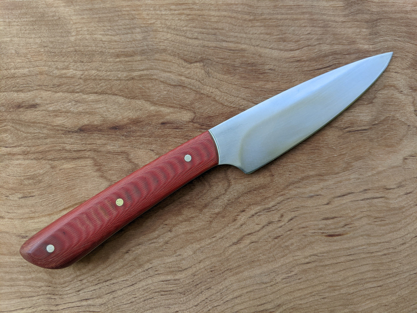 utility knife with red Micarta handle on wooden cutting board