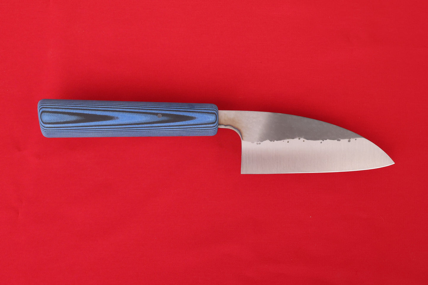 mid-size kitchen knife on red background. Blue and black SureTouch handle. Hammered finish on blade. 