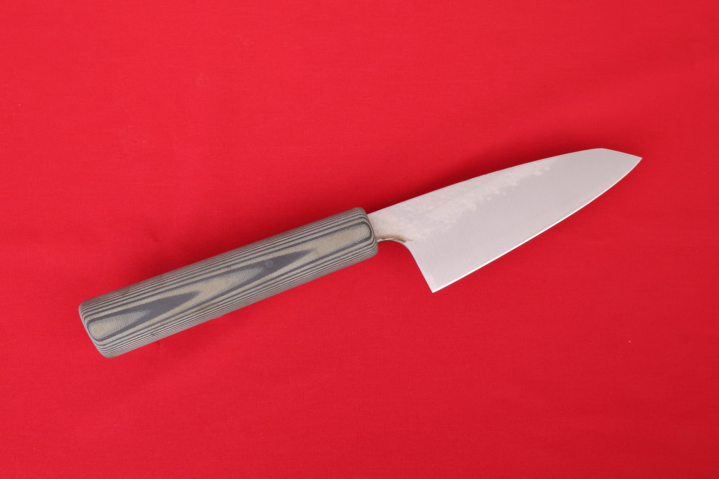 mid-size kitchen knife on red background. Petty with green and black SureTouch handle.