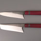 Set of two kitchen knives with Purple Hart wooden handles on gray background.