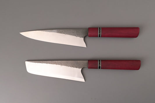 Set of two kitchen knives with Purple Hart wooden handles on gray background.