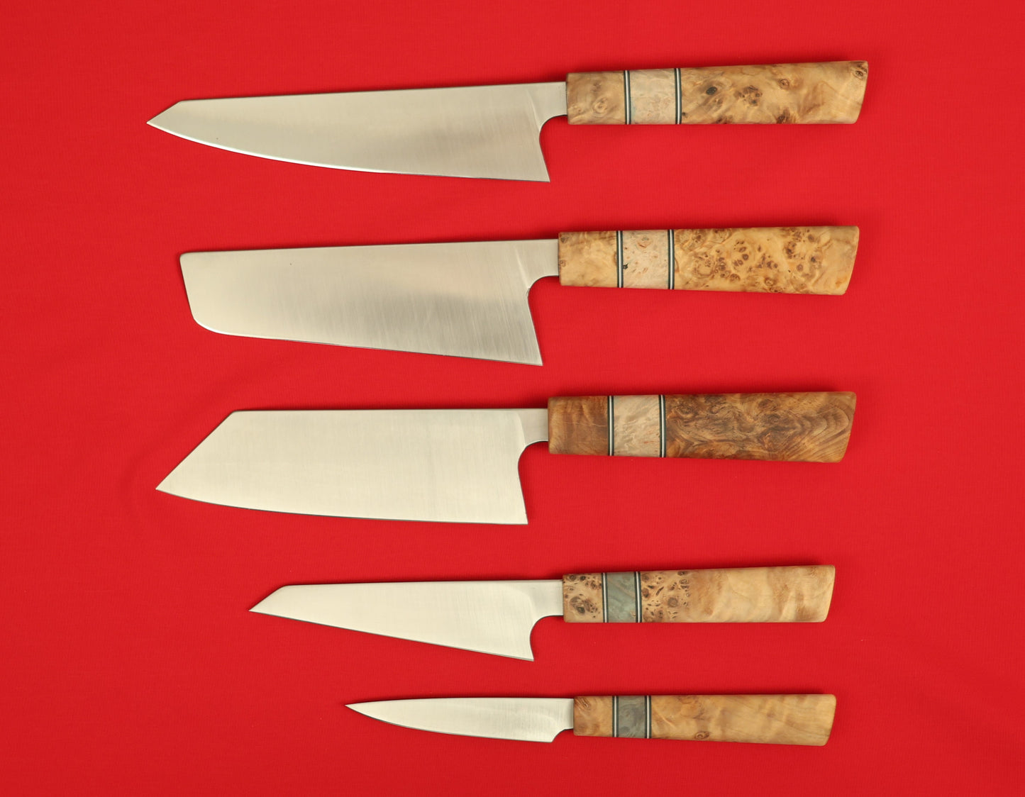 Japanese style kitchen knife set on a red background. Kiritsuke, Nakiri, Bunka, Honesuki and paring knives. 