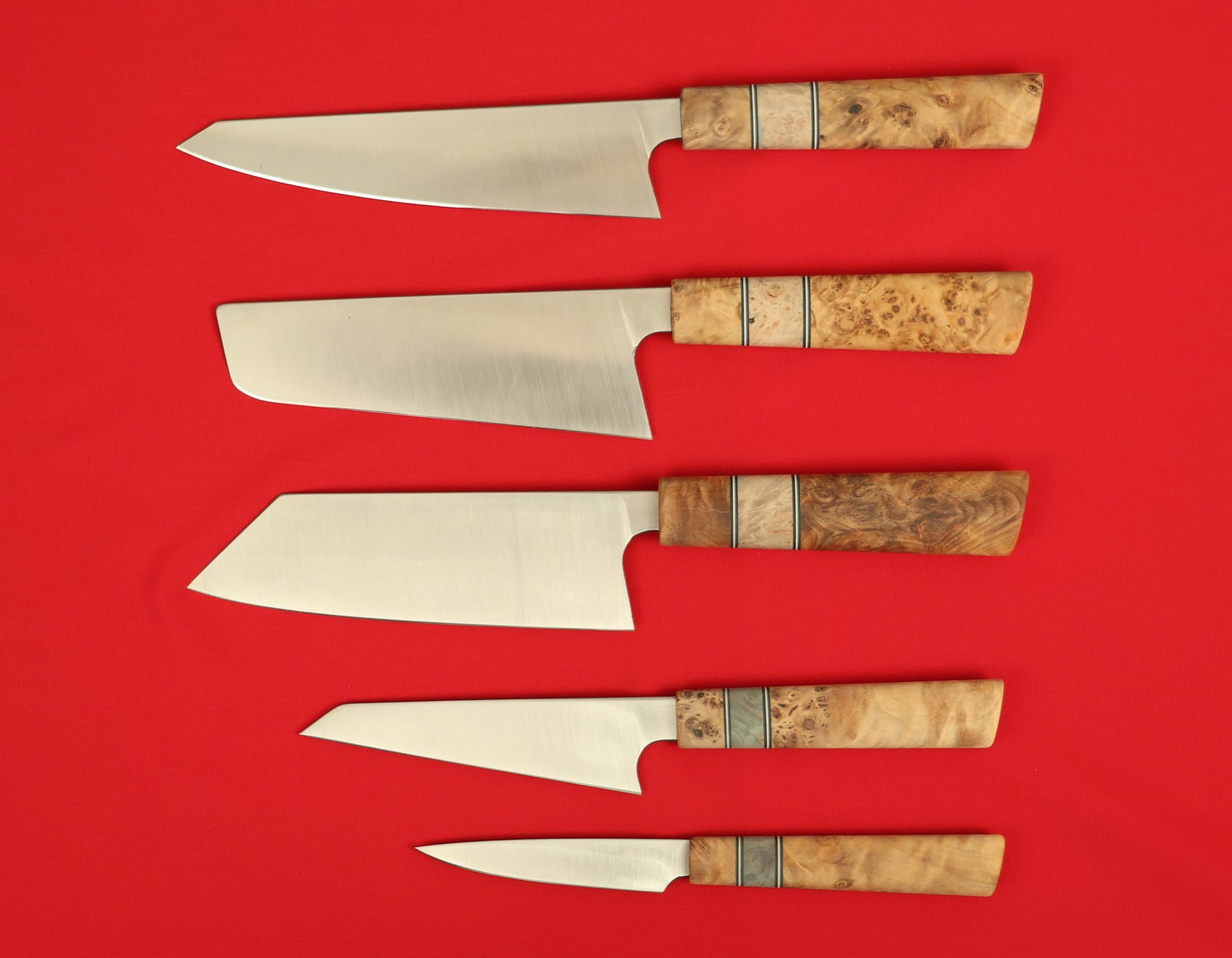 Japanese style kitchen knife set on a red background. Kiritsuke, Nakiri, Bunka, Honesuki and paring knives. 