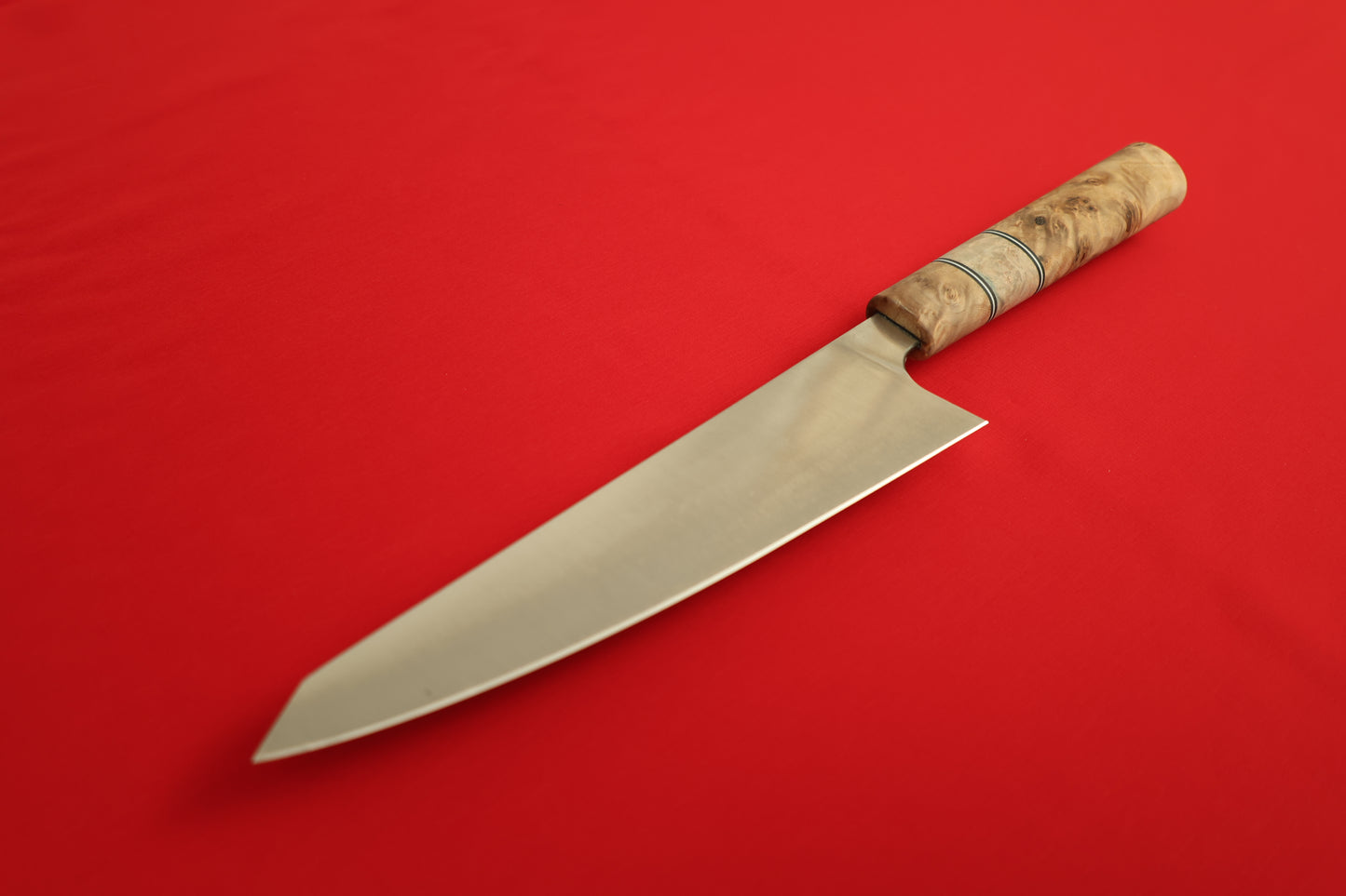 Kiritsuke with wooden handle on red background.