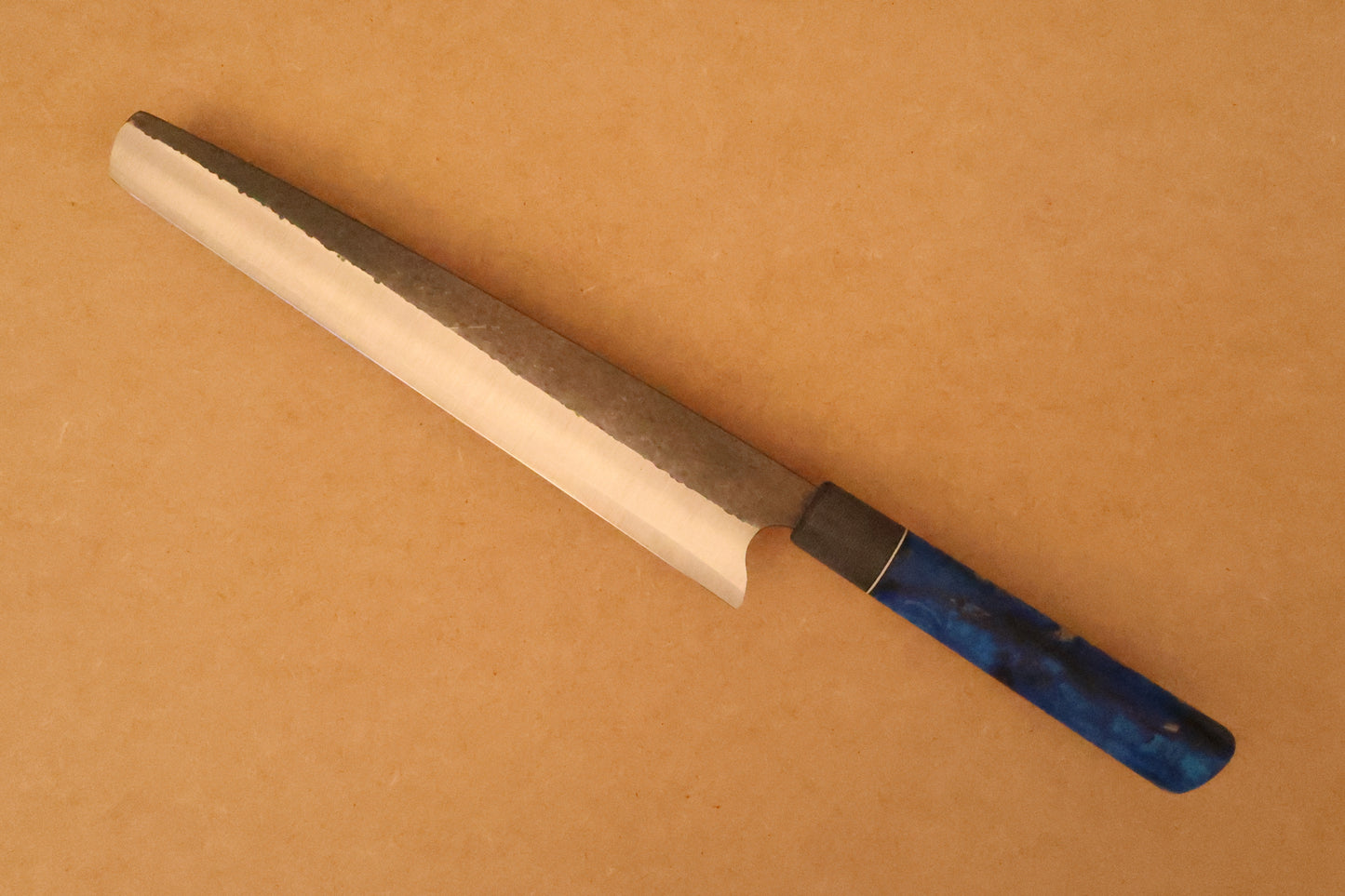 Slicer with blue resin handle on a beige background