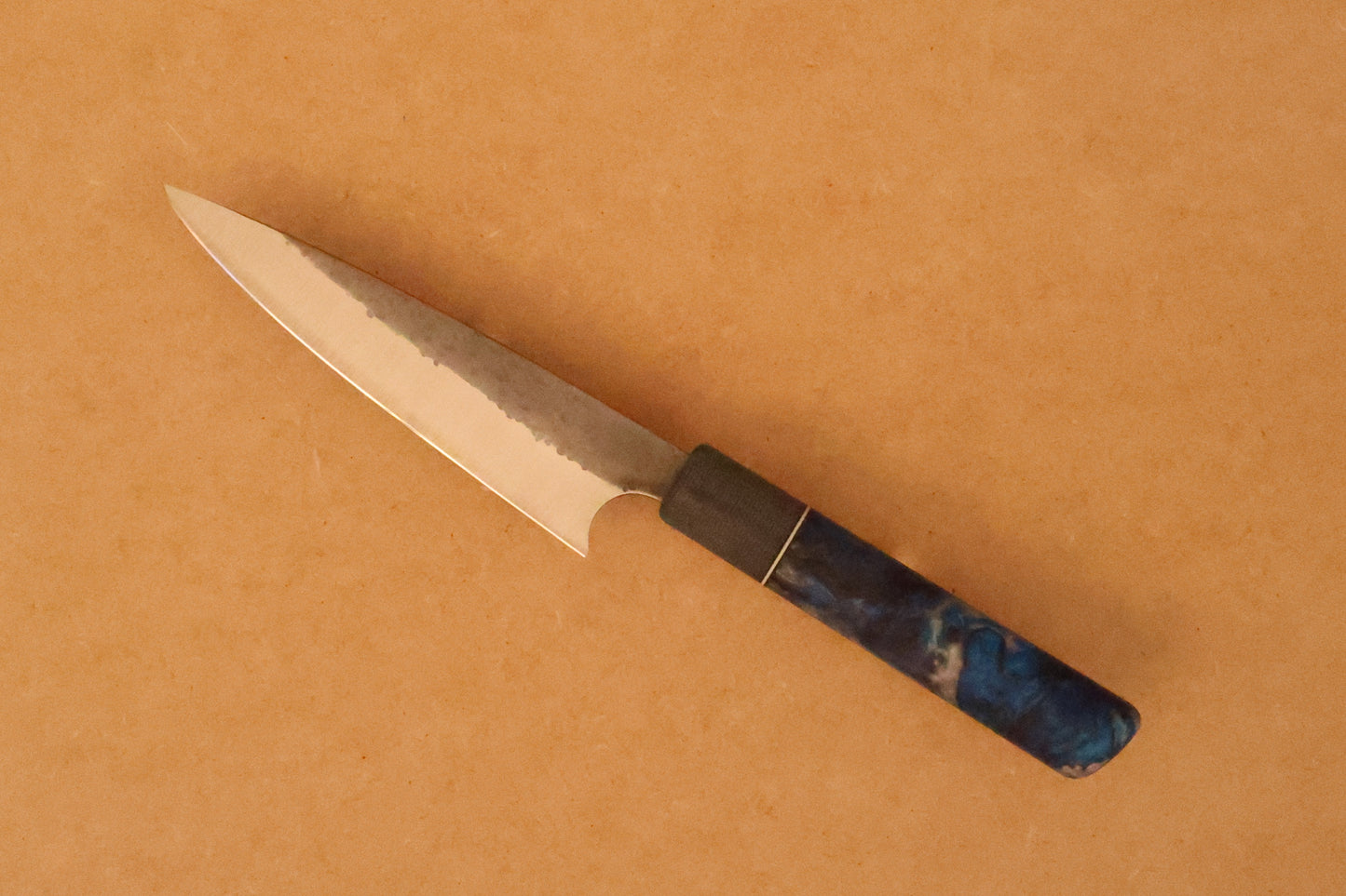 Petty knife with resin handle on a brown background