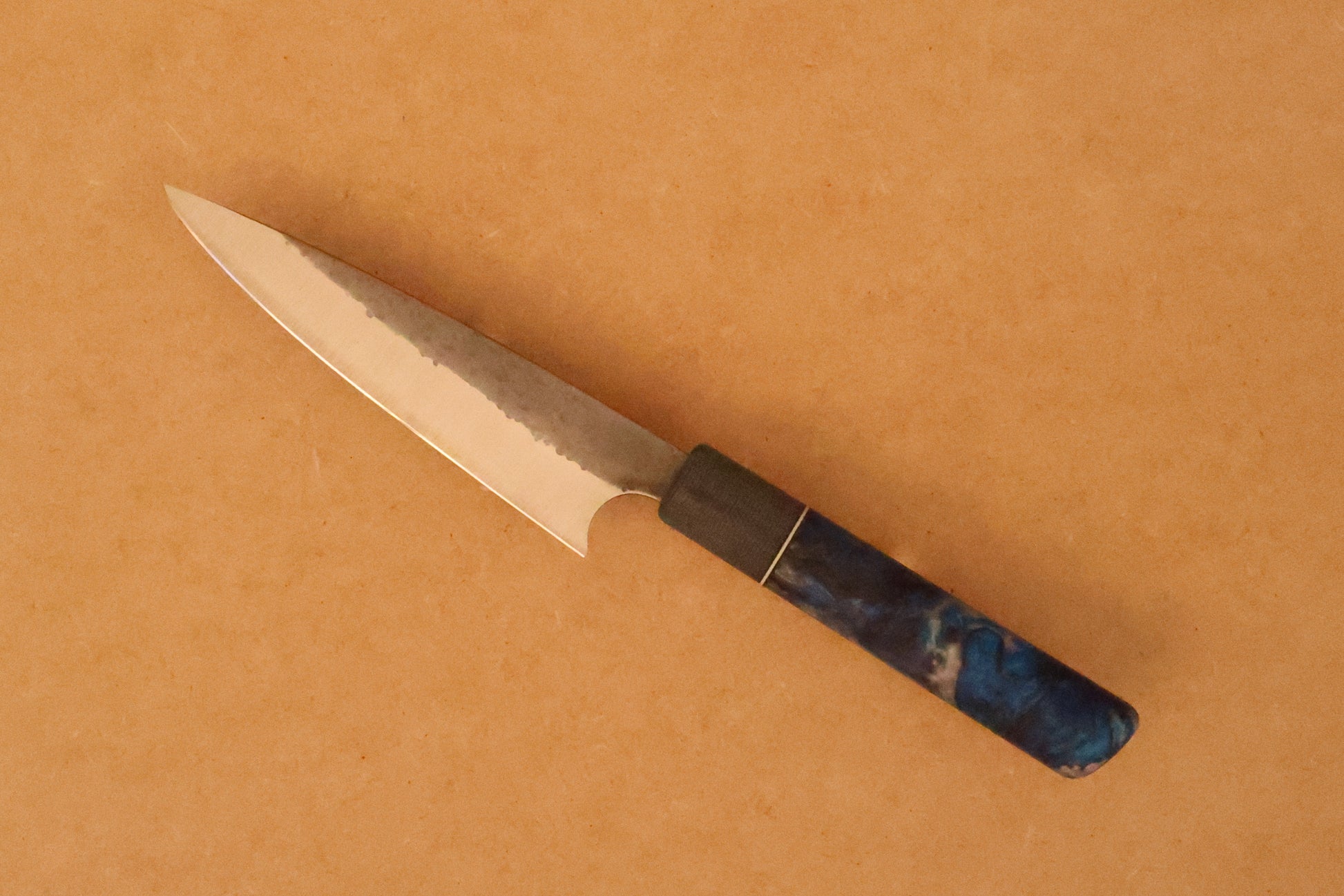 Petty knife with resin handle on a brown background