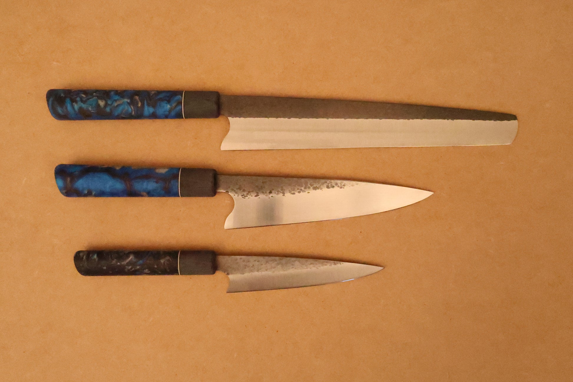 Three knives with decorative handles on a brown background
