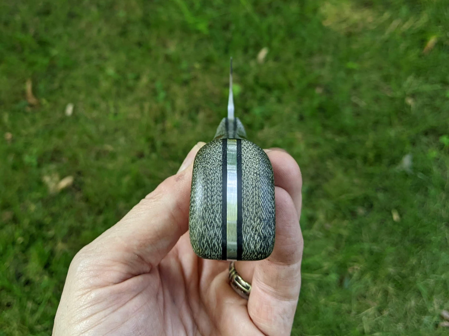 Choil shot of Santoku on green grass background