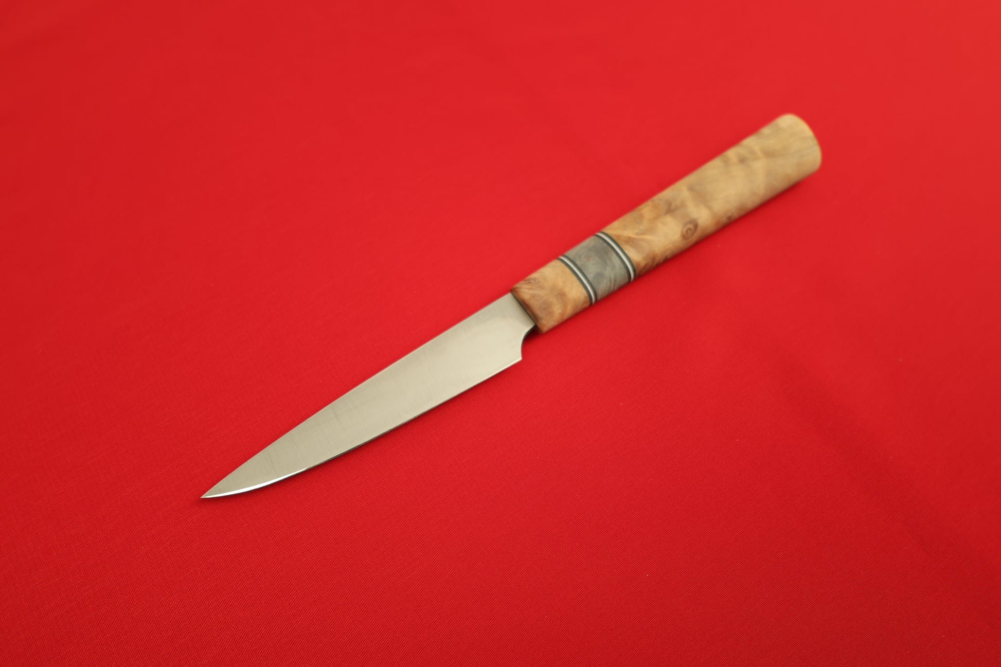 Paring knife with wooden handle on a red background.