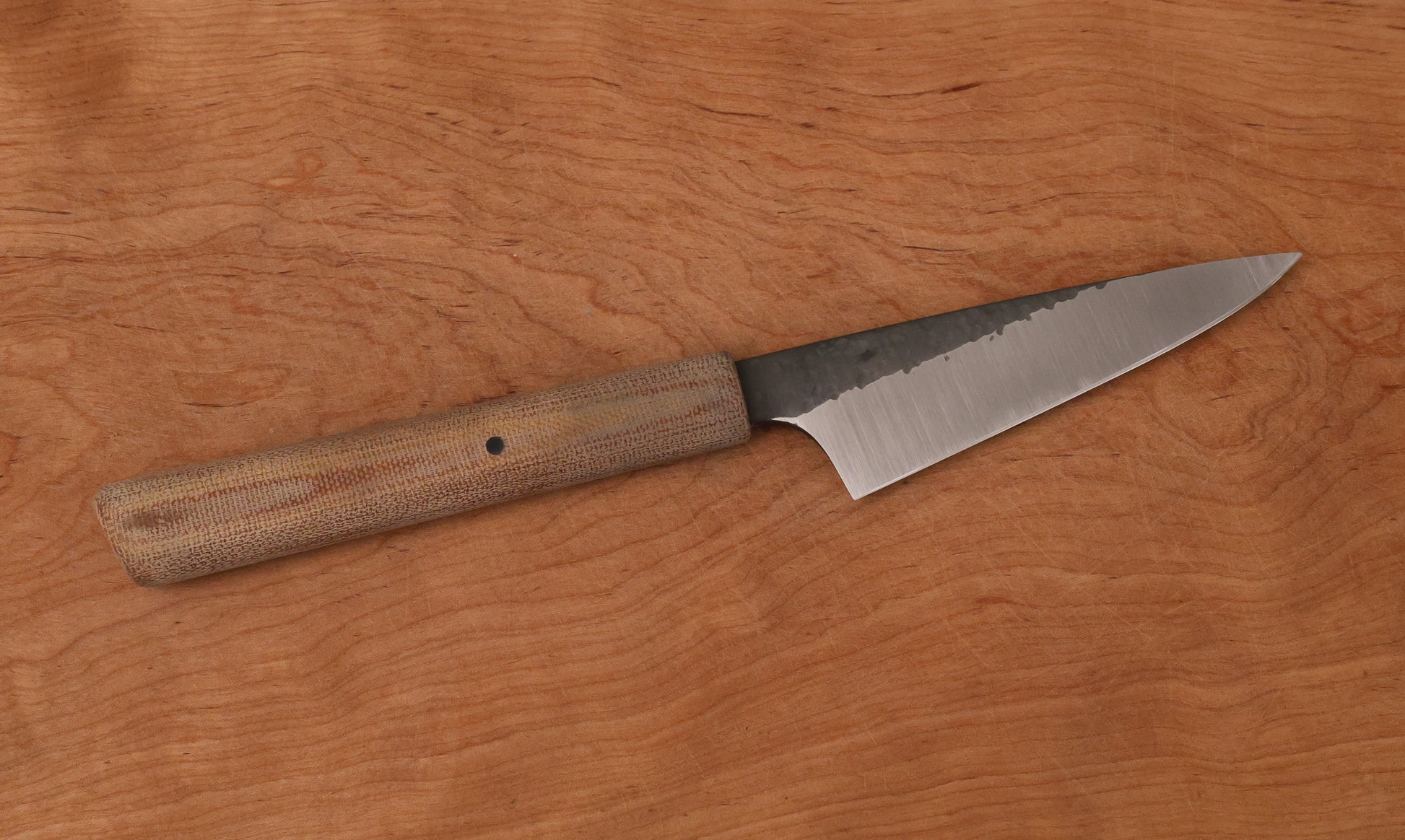 small kitchen knife with Micarta handle on a wooden cutting board