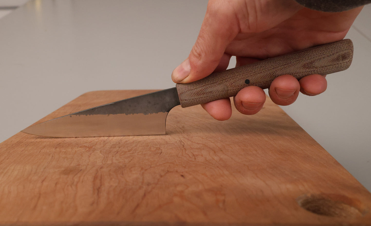 small kitchen knife handheld on a wooden cutting board