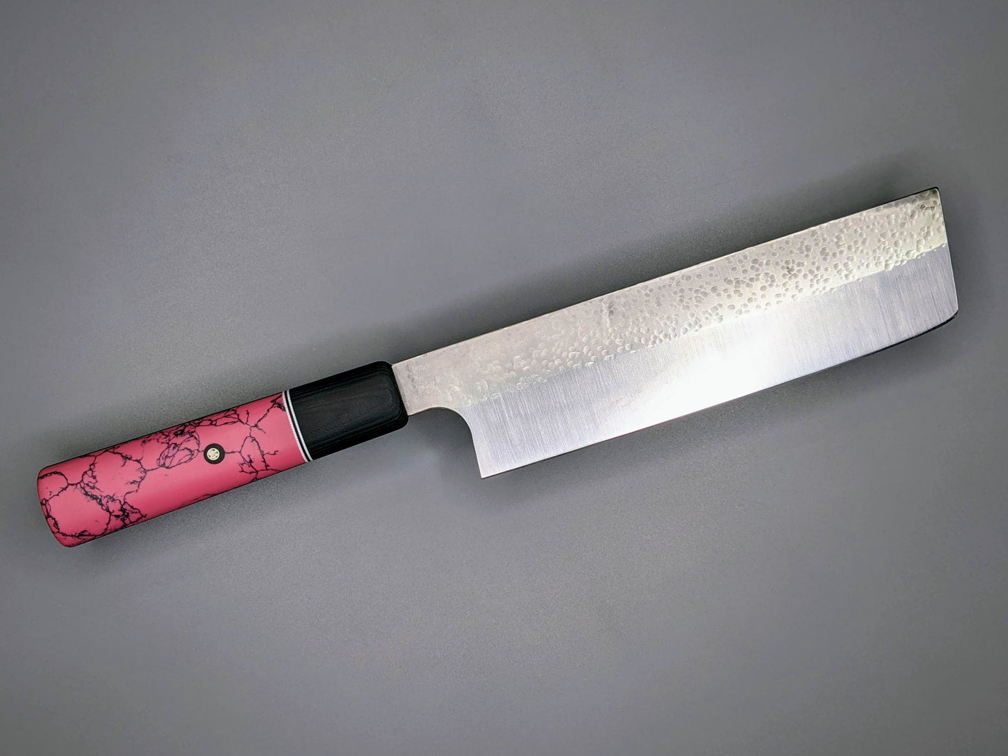 Japanese Nakiri with pink handle on a gray background.