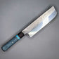 Japanese style Nakiri with a thick spine and blue handle on a gray background.