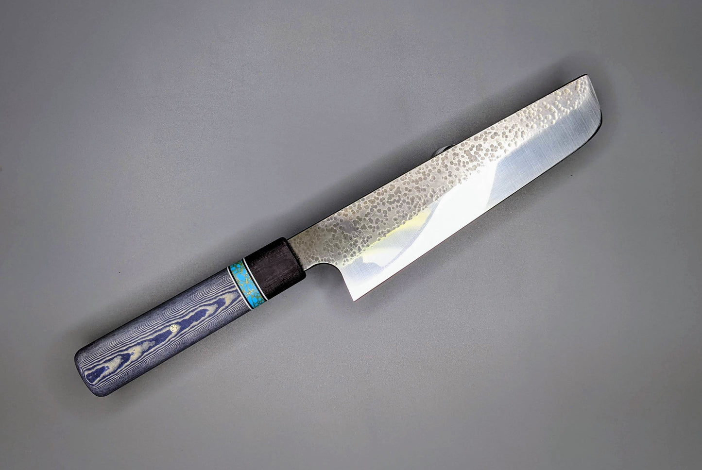 Japanese style kitchen knife with blue handle and hammered finish on blade 