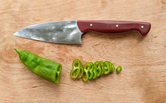 kitchen knife and pepper slices on wooden cutting board