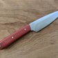 utility knife with red Micarta handle on wooden cutting board 